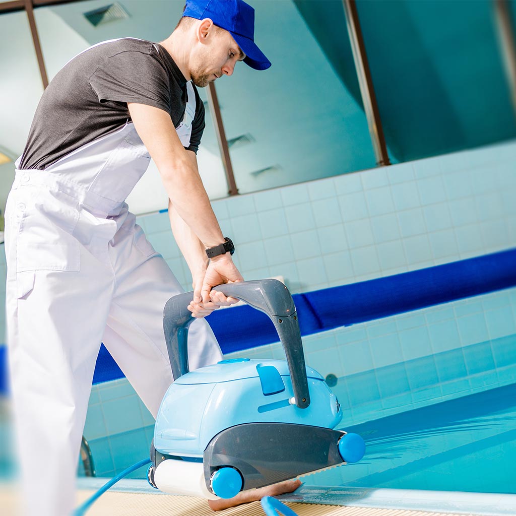 man cleaning swimming pool with pool vacuum