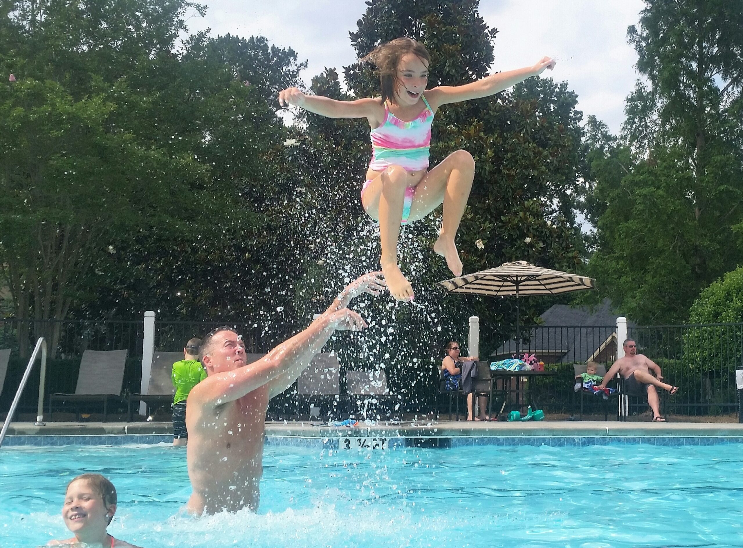 Dad throwing his daughter into the pool