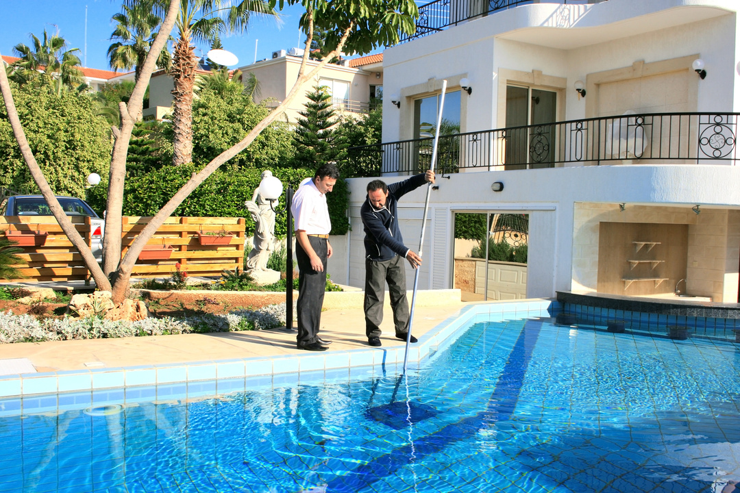Two men cleaning a pool
